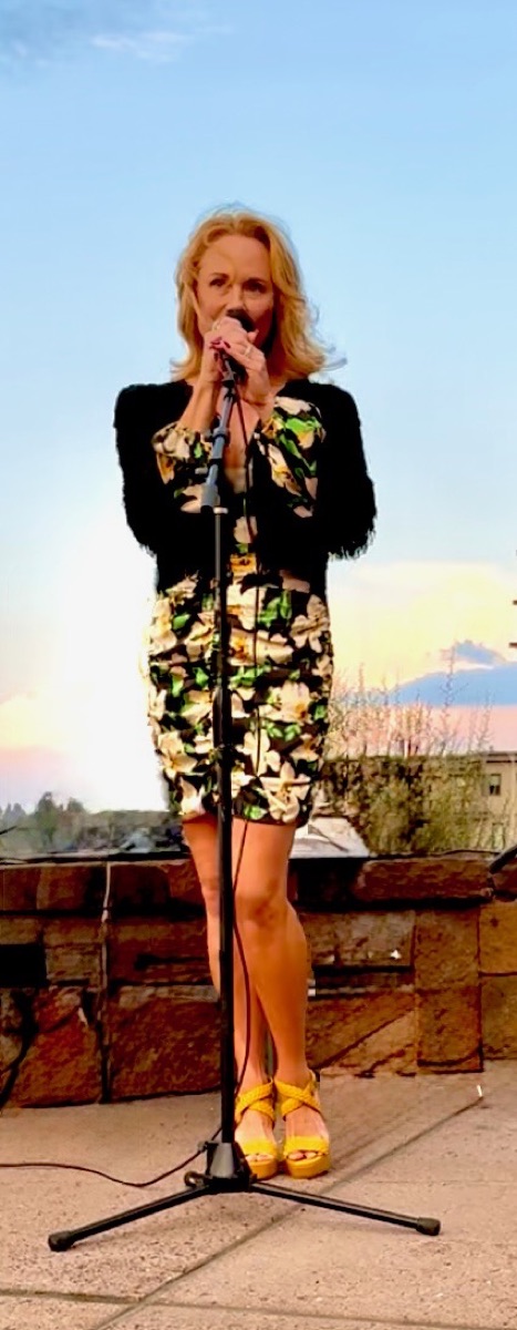 Deone Jennings singing at an outdoor microphone at dusk